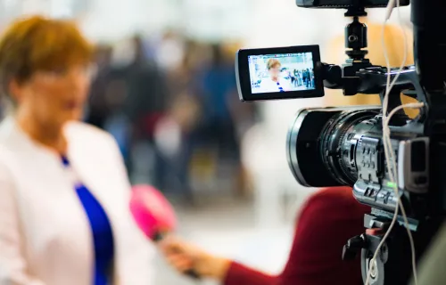 Eine Frau wird von einem Reporter interviewt und mit Kamera aufgenommen
